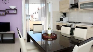 A modern kitchen with a dining table, chairs, a TV, and a view of the outside. - Remarkable 2-Bed Apartment in Srima with sea view (Srima)