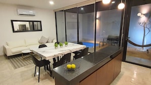 A modern dining area with a marble table, black chairs, and a fruit bowl. - Casa BJ37 Mérida Norte, la mejor ubicación. (Mérida)
