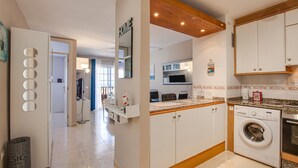 Une cuisine moderne équipée d’un lave-linge intégré, d’un four à micro-ondes et dotée d’un plafond en bois.