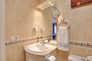 A bathroom with a sink, mirror, towel rack, and toilet.