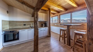A kitchen with wooden beams, a stove, and a view of mountains through large windows. - Apartment "Malgorerhof Lavendel" with Mountain View, Wi-Fi, Balcony & Shared Garden (Jenesien)