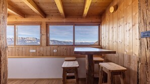 A wooden interior with a high ceiling, large windows, and a wooden table with stools. - Apartment "Malgorerhof Lavendel" with Mountain View, Wi-Fi, Balcony & Shared Garden (Jenesien)