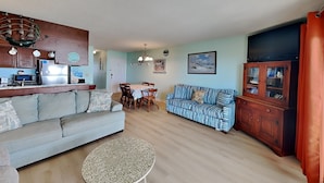 Ein Wohnzimmer mit einer Couch, einem Esstisch, einem Schrank und einem kleinen runden Tisch.