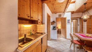 Eine Küche mit Holzausstattung, einem Spülbecken und einem Essbereich mit Tisch und Stühlen.