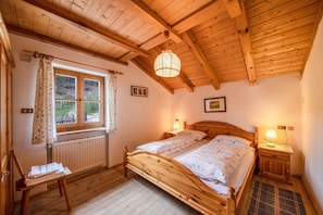 Une chambre à coucher avec un cadre en bois, un grand lit, une fenêtre avec des rideaux, un radiateur et une table de chevet en bois avec une lampe.