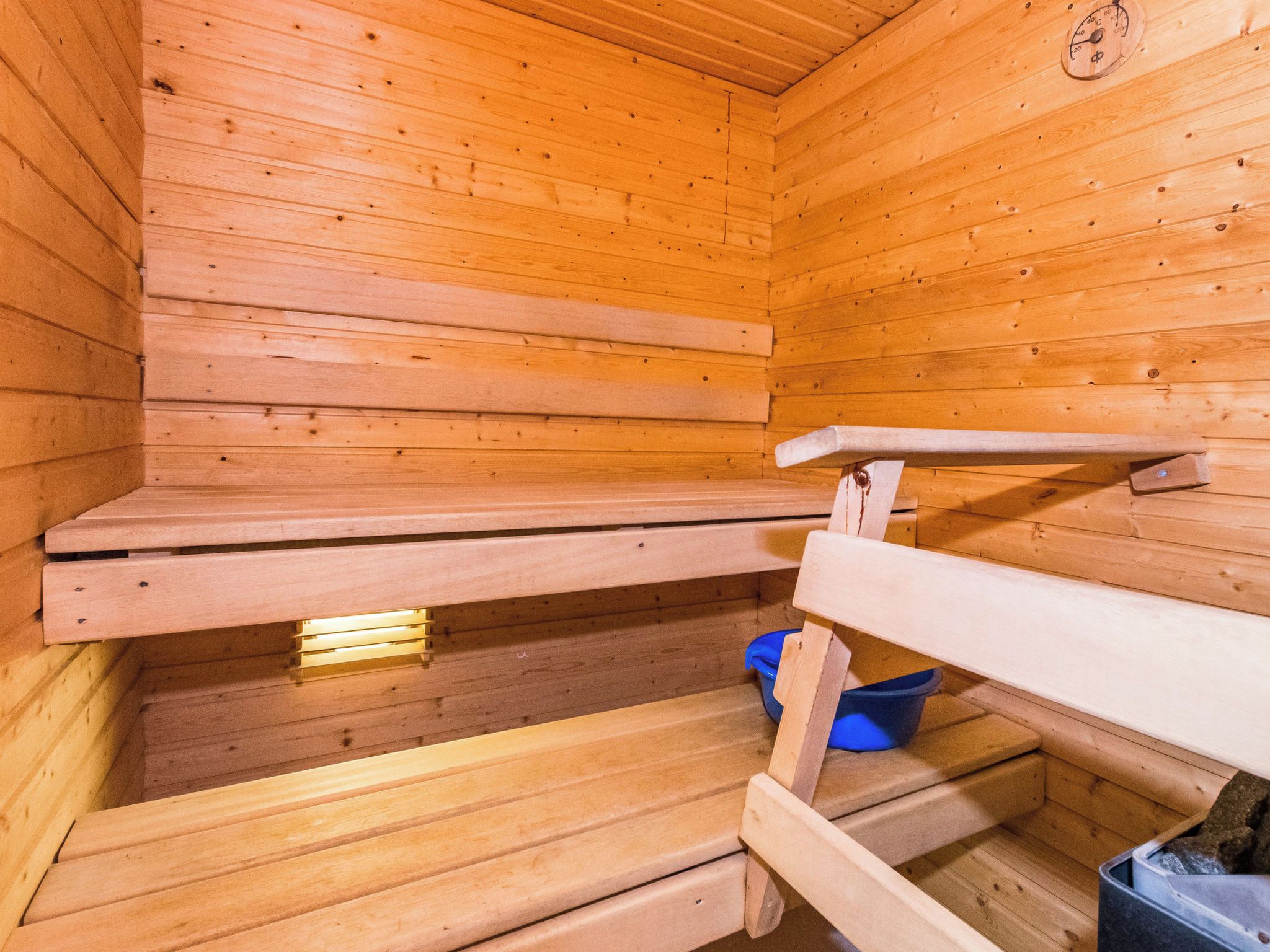 Un sauna en bois avec des bancs et un seau bleu.