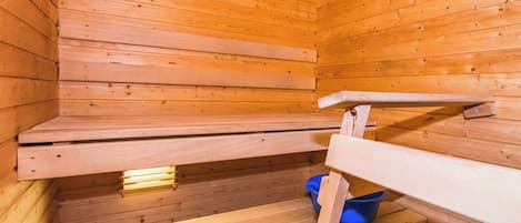 Eine Holzsauna mit Bänken und einem blauen Eimer.