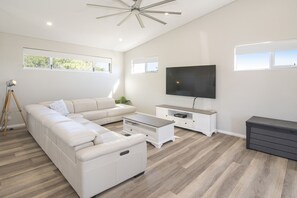 Relax in this stylish living room with a large L-shaped sofa, flat-screen TV, and storage.