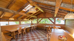 A rustic wooden dining area with checkered flooring, wooden benches, and tables. - Vacation Apartment "Malgorerhof Mathilde" with Mountain View, Wi-Fi and Balcony (Jenesien)