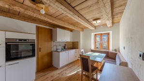 A kitchen with wooden beams, a dining area with a table and chairs, and a window with a view. - Vacation Apartment "Malgorerhof Mathilde" with Mountain View, Wi-Fi and Balcony (Jenesien)