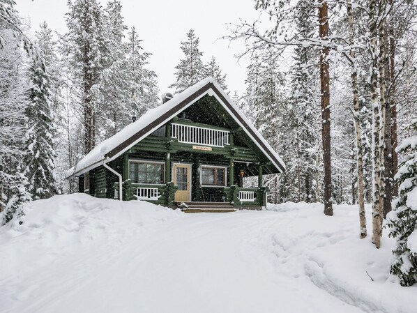 A log cabin with a front porch, surrounded by snow-covered trees. - Metsätähti by Interhome (Puolanka)