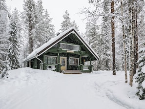 A log cabin with a front porch, surrounded by snow-covered trees. - Metsätähti by Interhome (Puolanka)