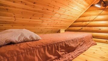 L’intérieur d’une cabane en bois, avec un lit, un oreiller et un plafond en pente.