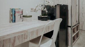 A modern kitchen with a marble countertop, a white chair, a black refrigerator, and a small potted orchid. - Dparagon Pogung F (Depok)