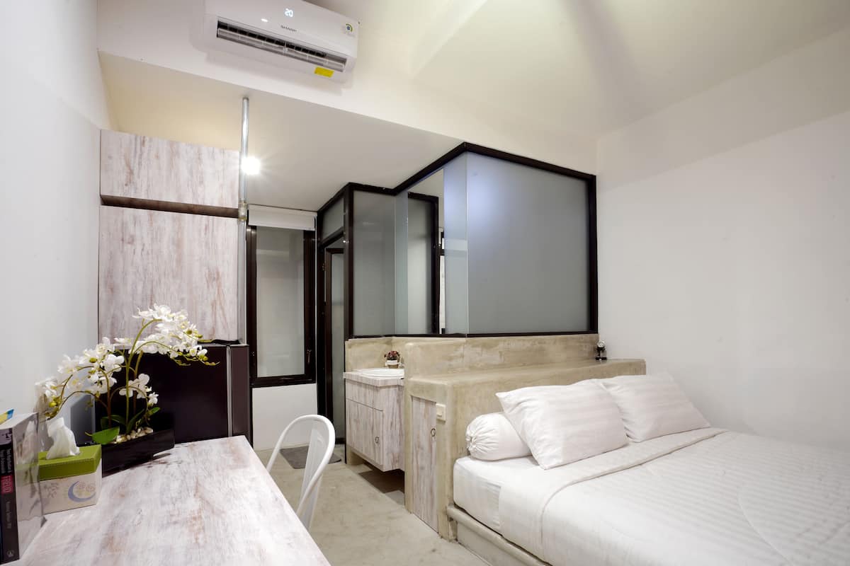 A modern bedroom with a bed, bedside table, and a mirror.