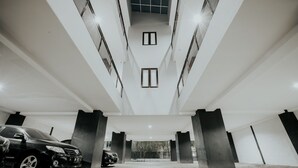 A modern parking garage with a clean, minimalist design, featuring concrete pillars and a geometric ceiling structure. - Dparagon Pogung F (Depok)