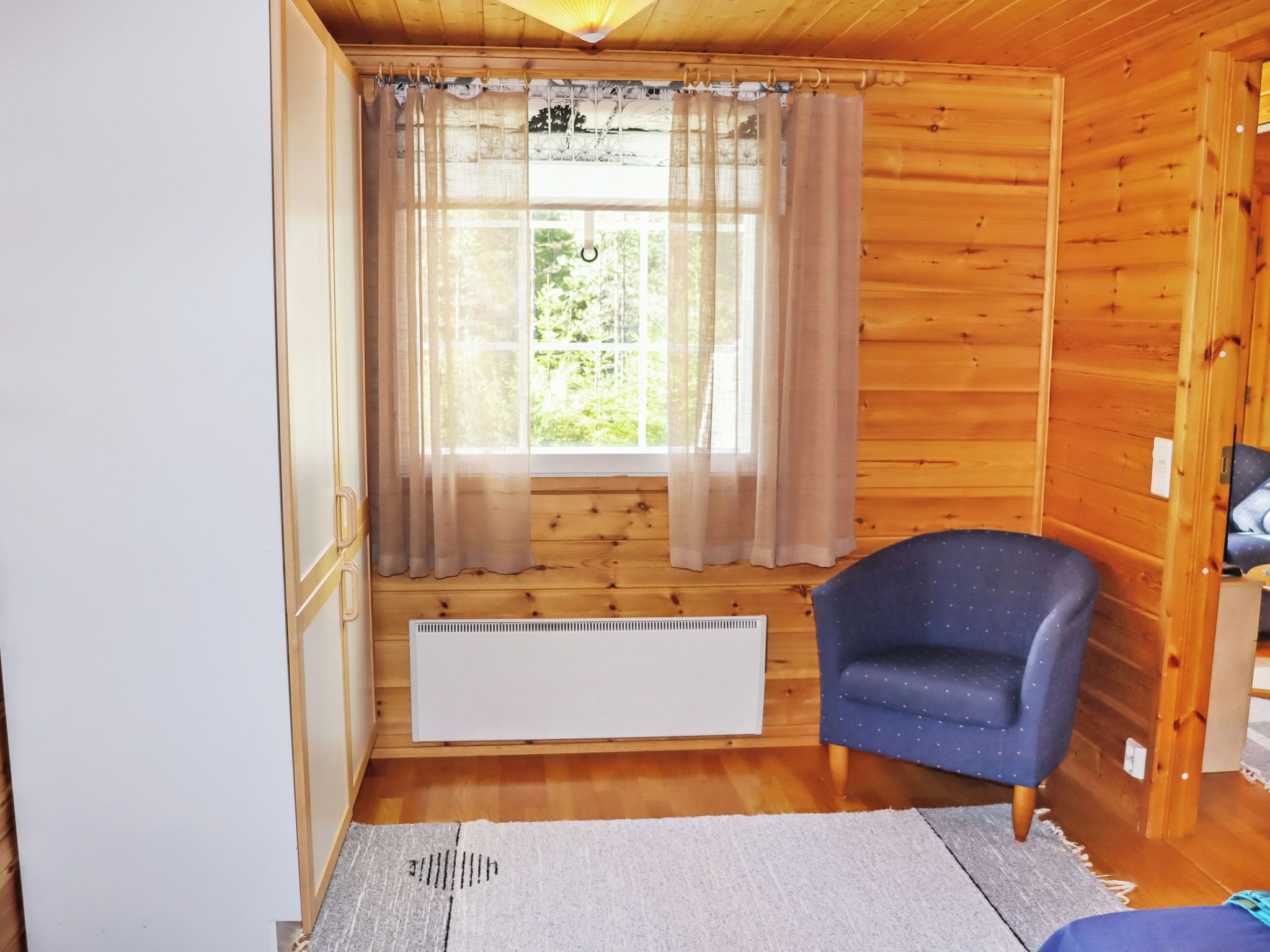 A room with a window, a radiator, a chair, and a bed.