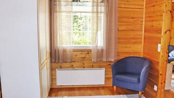 A room with a window, a radiator, a chair, and a bed.