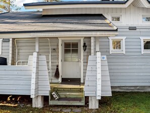 Een gelijkvloers huis met een veranda, een deur en een kleine trap naar de ingang.