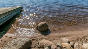 A clear lake with a wooden dock extending into the water, surrounded by rocks and pebbles. - Rantalinna 2 by Interhome (Ruokolahti)