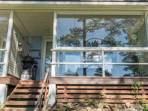 A wooden staircase leading to a porch with a large glass window reflecting trees. - Rantalinna 2 by Interhome (Ruokolahti)