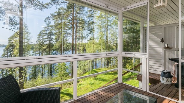 A wooden deck with glass railings overlooking a lake and forest. - Rantalinna 2 by Interhome (Ruokolahti)