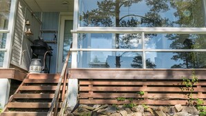 A wooden staircase leading to a porch with a large window reflecting trees. - Rantalinna 2 by Interhome (Ruokolahti)