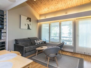 A modern living room with a grey sofa, a small round table, and a grey armchair. There is a painting on the wall and a window with blinds. - Rantalinna 2 by Interhome (Ruokolahti)