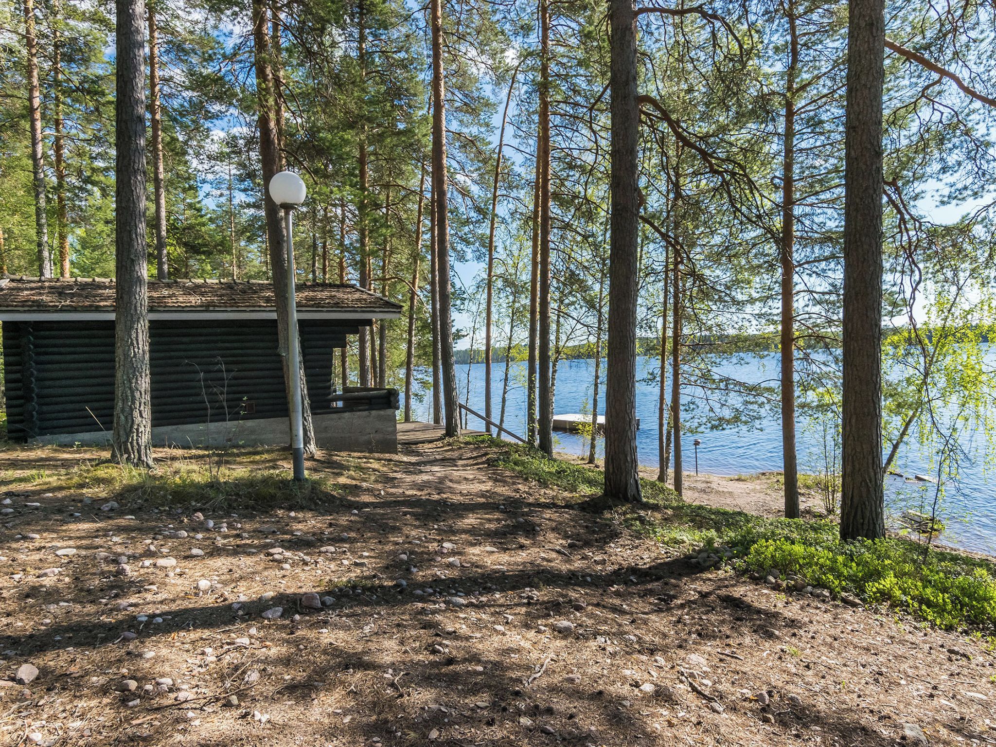 Une cabane avec un quai qui s’avance dans un lac, entourée d’arbres.