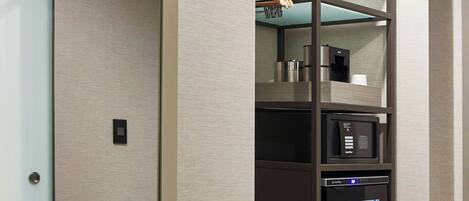 A modern interior with a built-in microwave, a small refrigerator, and a wooden shelf unit.