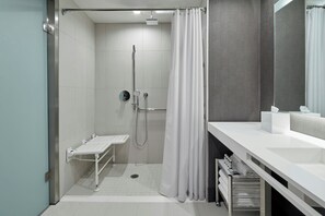 A modern bathroom with a shower, a sink, and a mirror.