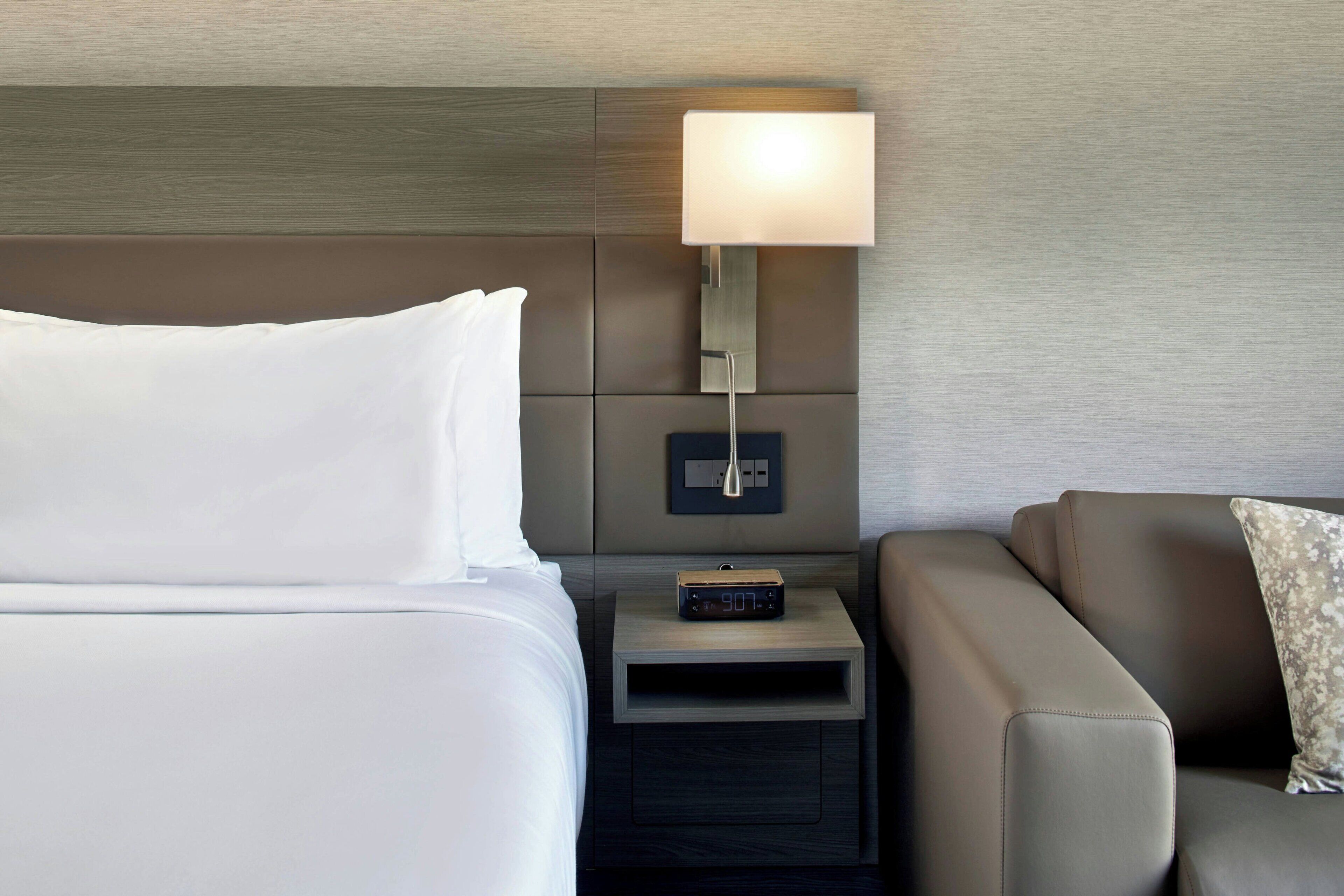 Ein Hotelzimmer mit einem Bett, einem Nachttisch mit Lampe und einem Sofa.