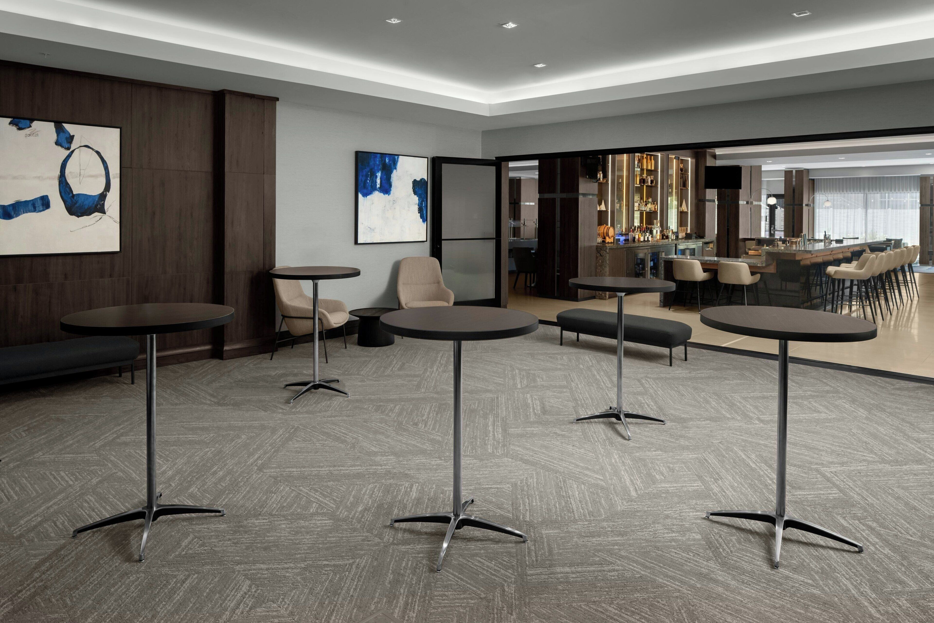 Een moderne hotel lobby met ronde tafels, comfortabele zithoeken en kunstwerken aan de wanden.