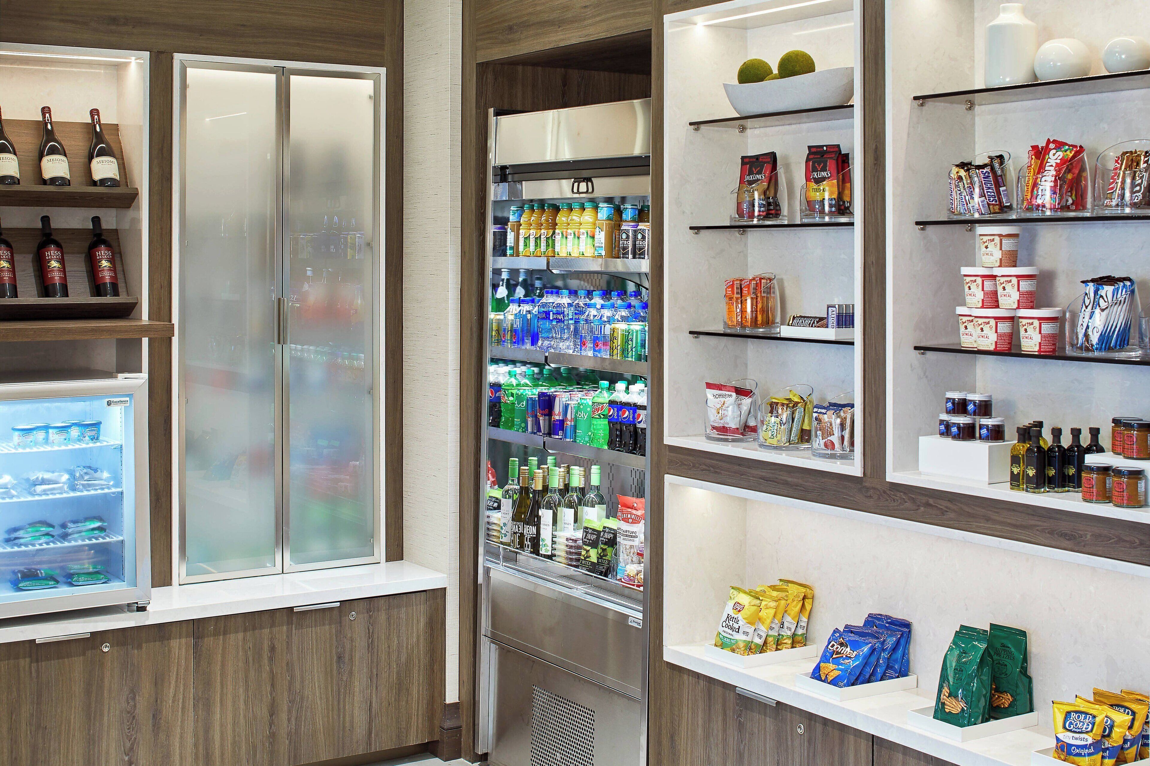 A well-stocked beverage refrigerator with various drinks, a selection of snacks, and a wine cooler with bottles.