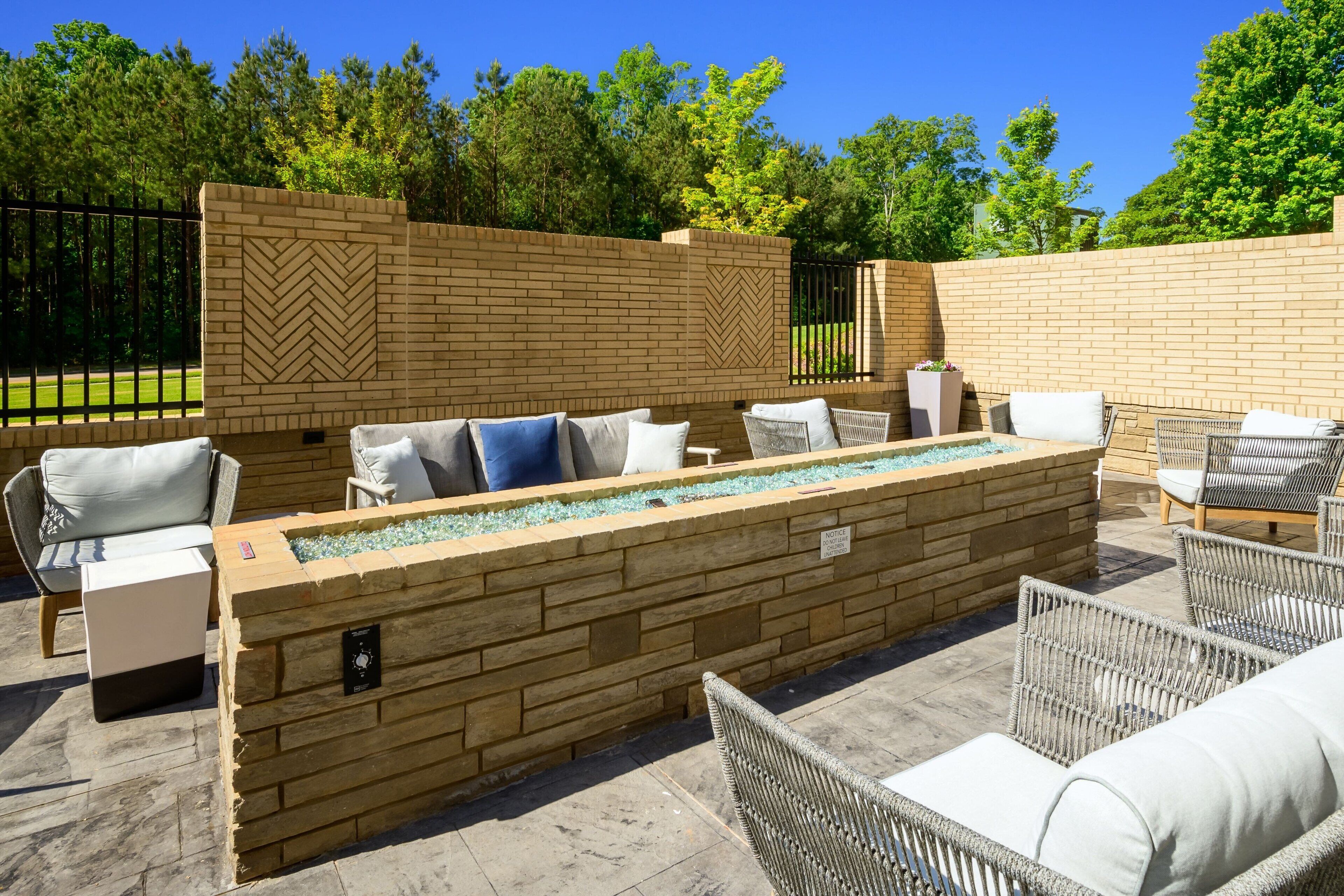 An outdoor patio with wicker furniture, a rectangular water feature, and a brick wall.