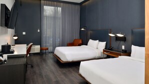 A modern hotel room with two beds, a desk, a chair, and a TV mounted on the wall. - Courtyard by Marriott Raleigh Cary Crossroads (Cary)