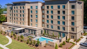 A multi-story hotel with a courtyard pool, outdoor seating, and a well-maintained lawn. - Courtyard by Marriott Raleigh Cary Crossroads (Cary)