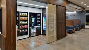 A modern lobby with a seating area, vending machines, and a refrigerated display. - Courtyard by Marriott Raleigh Cary Crossroads (Cary)