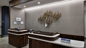 A reception desk with a modern design, a digital screen, and a sign indicating the hotel name. - Courtyard by Marriott Raleigh Cary Crossroads (Cary)