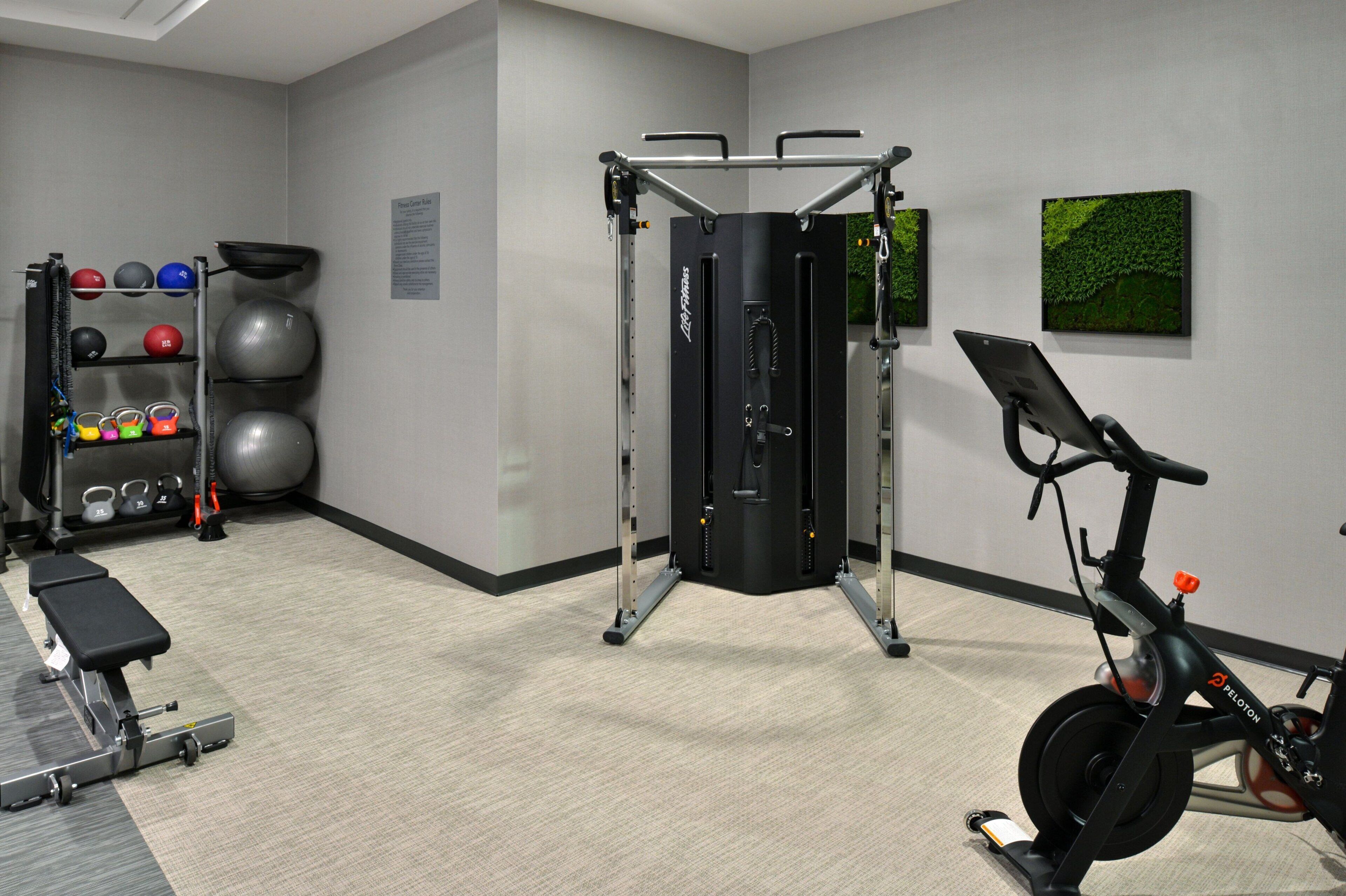 Un gimnasio con barra de dominadas, pelotas de ejercicio, banco y bicicleta estática.