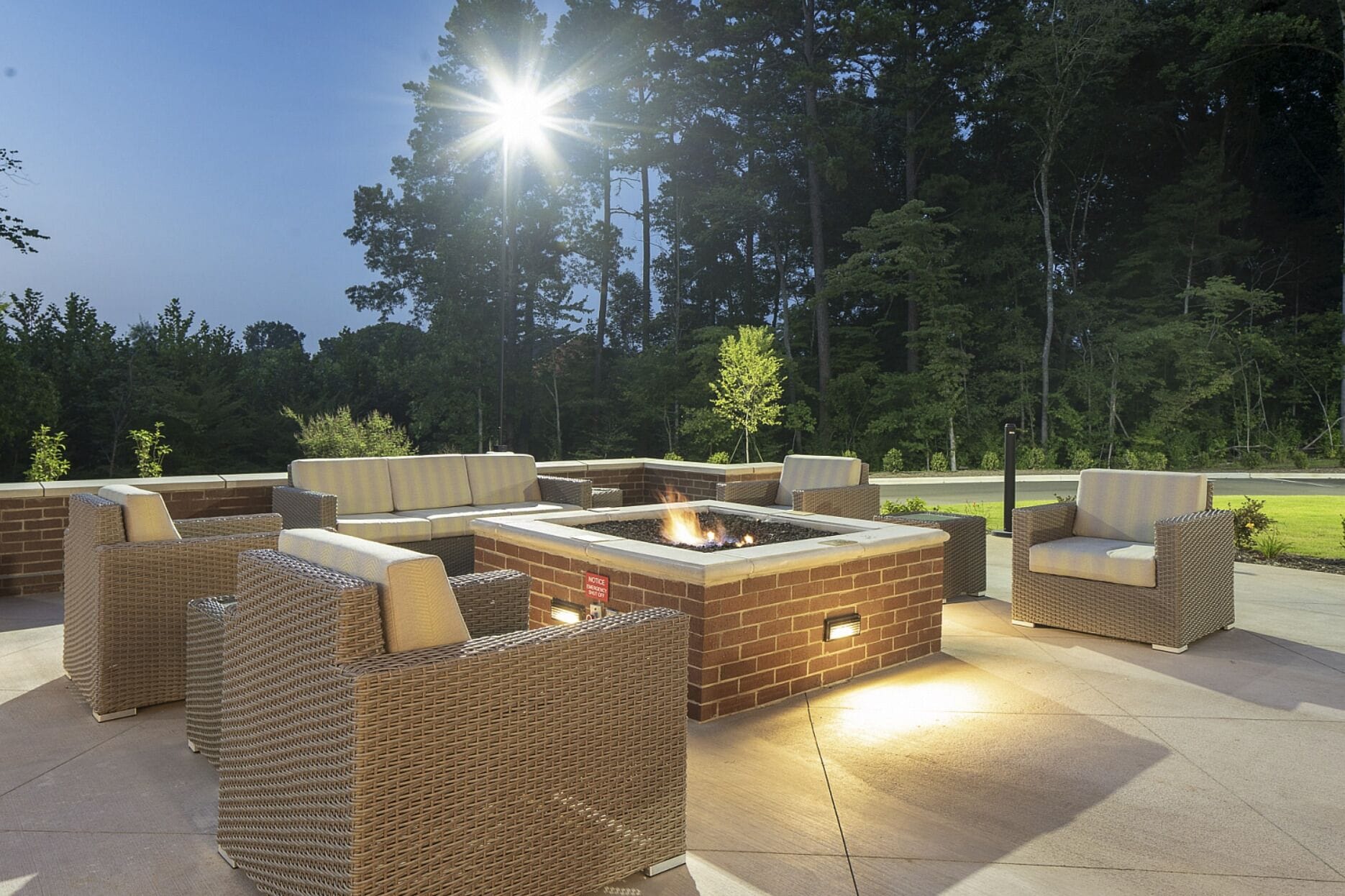 An outdoor patio with wicker furniture, a fire pit, and a brick fire table.