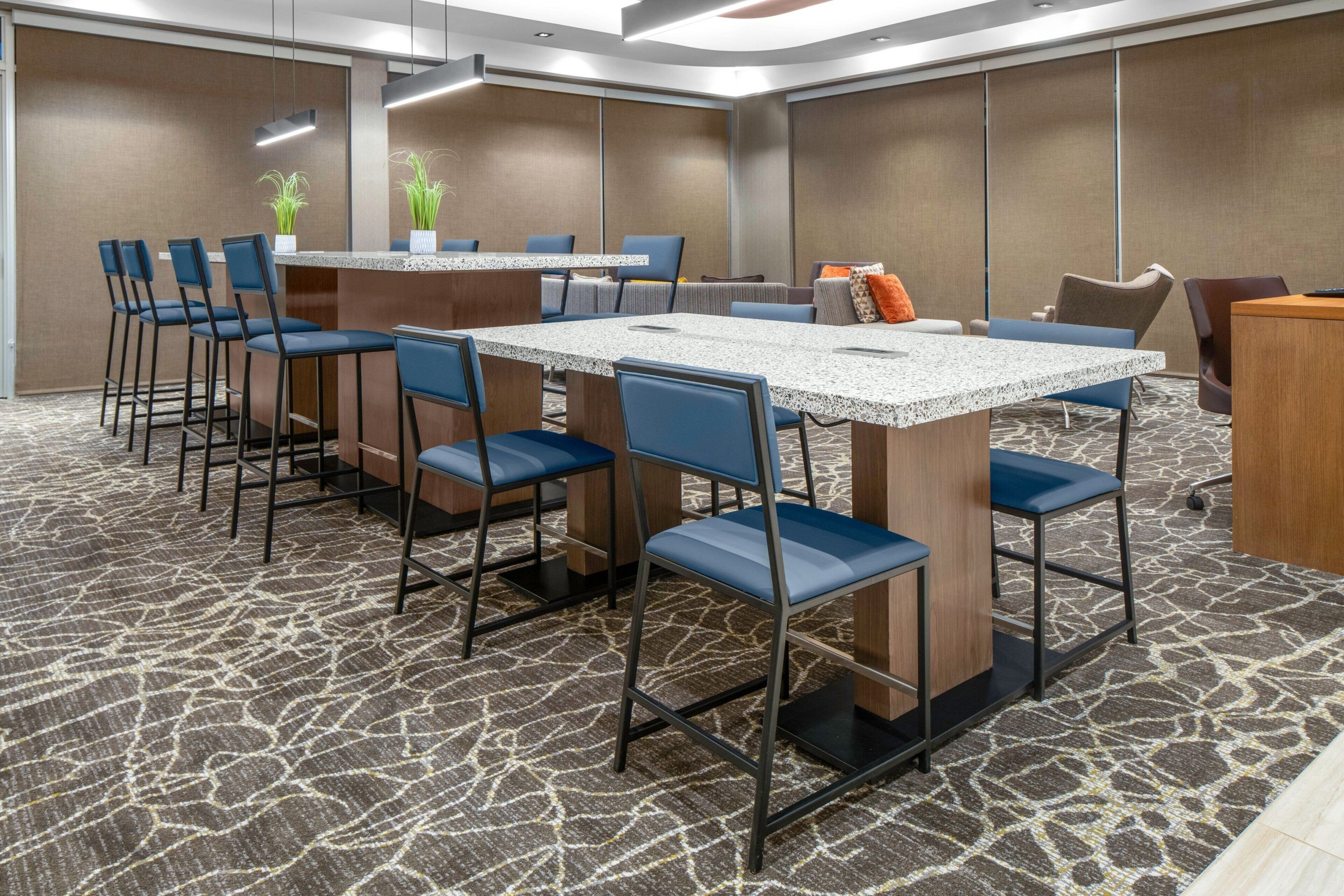 Una sala conferenze con un grande tavolo, sedie blu e pavimento rivestito di moquette.