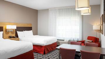 Ein Hotelzimmer mit zwei Betten, einem Schreibtisch und einem Stuhl.