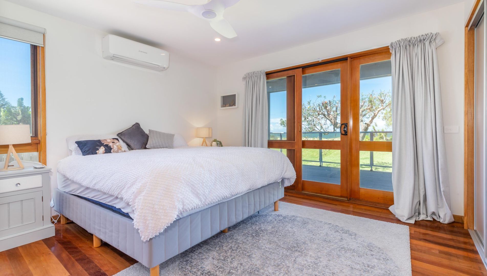Une chambre avec un grand lit, une table de chevet, une lampe et une vue sur l’extérieur grâce à une porte-fenêtre coulissante.