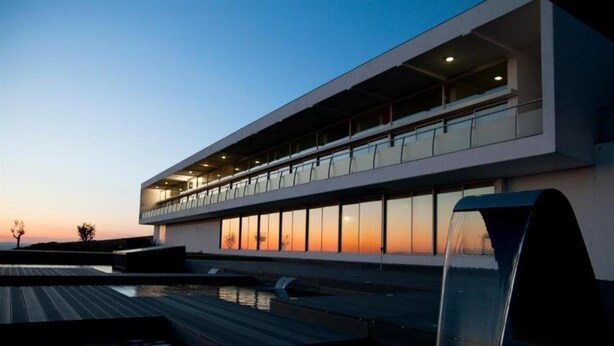 A modern building with a flat roof and large windows, overlooking a body of water. - Hotel And Spa Alfandega Da Fe (Alfandega da Fe)