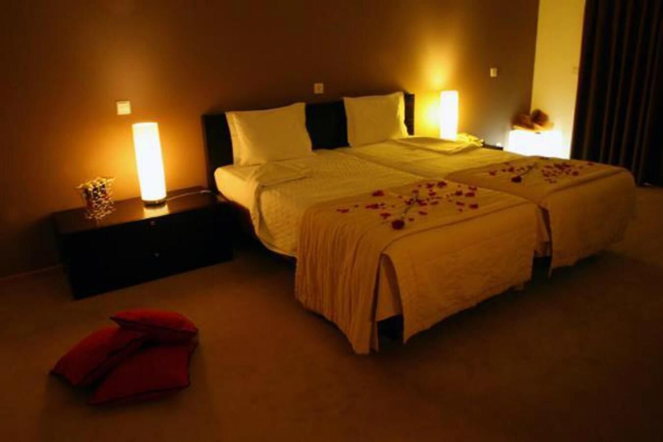 Quarto de hotel com duas camas, uma mesa de cabeceira e uma cadeira vermelha.