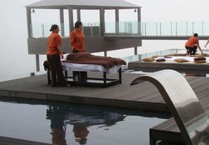 A spa area with a massage table, a pool, and a view of the ocean. - Hotel And Spa Alfandega Da Fe (Alfandega da Fe)