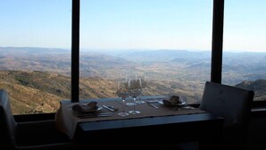 A table set for dining with wine glasses and a laptop, overlooking a mountainous landscape. - Hotel And Spa Alfandega Da Fe (Alfandega da Fe)