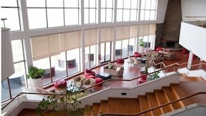 A spacious interior with a staircase leading to an upper level, large windows, and a variety of seating arrangements. - Hotel And Spa Alfandega Da Fe (Alfandega da Fe)