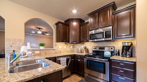 A modern kitchen with granite countertops, stainless steel appliances, and dark wooden cabinets. - Bikers Paradise , Trails, Promenade Mall, AMP, Restaurants, and Top Golf (Rogers)